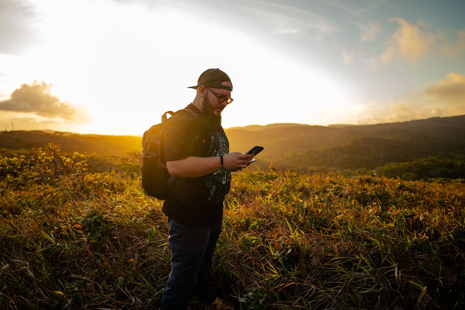 Hombre con mochila en un campo al atardecer