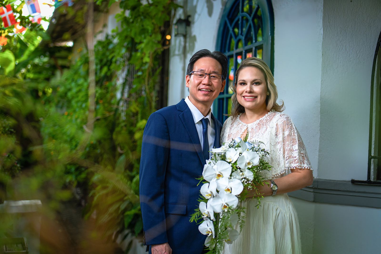 Novios sonriendo con un ramo de orquídeas blancas