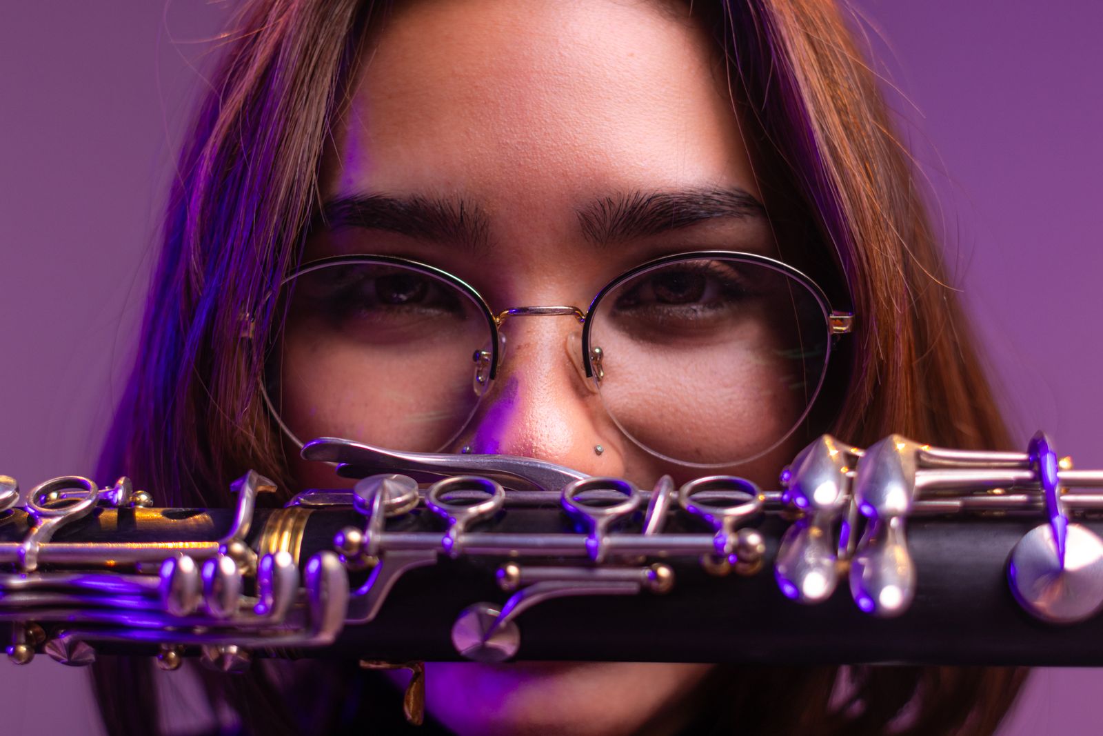 Primer plano de una mujer con lentes detrás de un clarinete