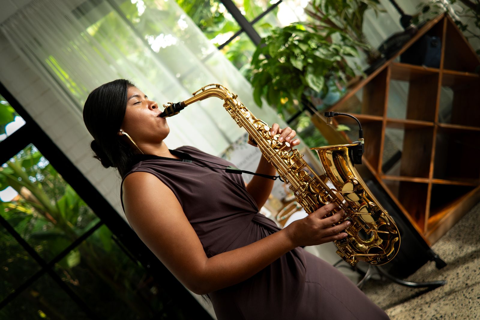 Mujer tocando el saxofón entre plantas